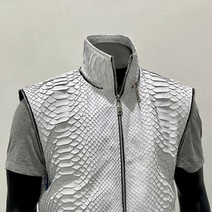 以下が含まれることがあります： ジッパー留めとヘビ革模様の白い革ベスト