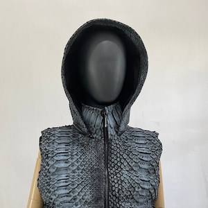 May include: A sleeveless hooded vest made of blue and black snakeskin. The vest has a zip fastening and a stand-up collar.