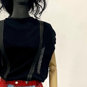 May include: Red and white snakeskin chaps with a flame design. The chaps are worn over a pair of light blue jeans.