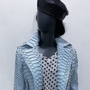 以下が含まれることがあります： ジッパー留めのライトブルーのスネークスキンレザーのジャケット。ジャケットはスタンドカラーと長袖です。