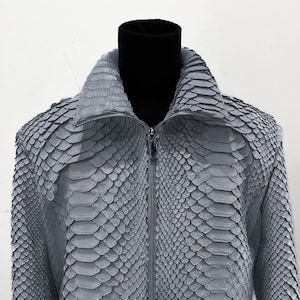 May include: A gray snakeskin jacket with a zipper closure. The jacket has a stand-up collar and long sleeves.