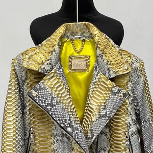 May include: A yellow and gray snakeskin leather jacket with a zipper closure and a belt at the waist. The jacket has a yellow lining and a label that says "Ohelo".