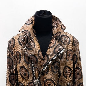 May include: A brown leather jacket with a snake skin pattern. The jacket has a zipper closure and a belt at the waist.