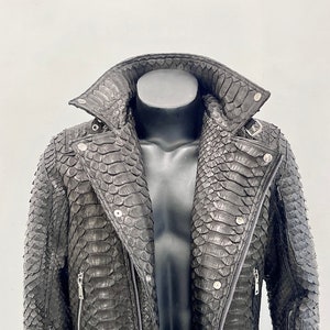 May include: A black leather jacket with a snakeskin pattern. The jacket features a zip fastening, a stand-up collar, and two pockets on the front.