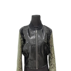 May include: A black and green bomber jacket with a zipper closure. The jacket is made of leather and has a snakeskin pattern.