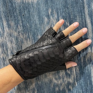 May include: Black leather fingerless gloves with a zipper detail. The gloves have a snakeskin pattern.