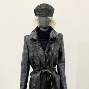 May include: A long black snakeskin coat with a belt and a matching black beret.