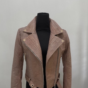 May include: A light brown snakeskin leather motorcycle jacket with a zipper closure, a belt, and gold hardware.