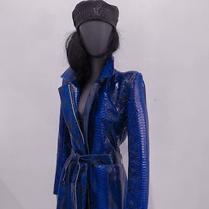 May include: A long blue snakeskin coat with a black belt and a black beret.