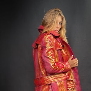 May include: A red and gold snakeskin trench coat with a belt.