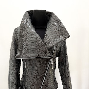 May include: A grey snakeskin leather jacket with a large, asymmetrical collar and a diagonal zip closure.