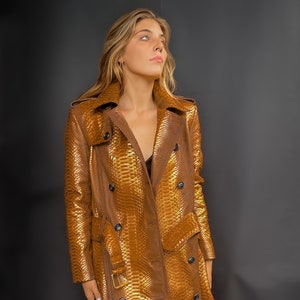 May include: A long, gold-colored snakeskin trench coat with a belt and button closure.