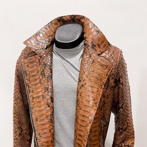 May include: A brown leather jacket with a snakeskin pattern. The jacket has a zip fastening and a collar.