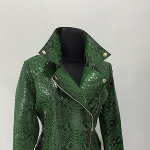May include: A green snakeskin leather jacket with a gold zipper and belt. The jacket has a classic biker style with a stand-up collar and a zippered front.