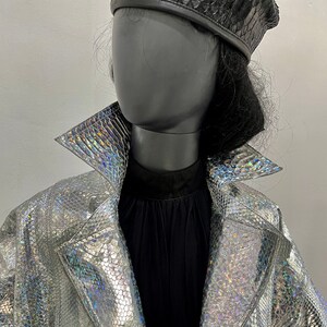 May include: A silver iridescent jacket with a snakeskin pattern. The jacket has a zip closure and a collar.