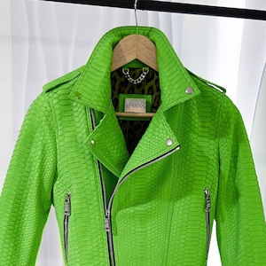 以下が含まれることがあります： ヘビ柄の鮮やかな緑色の革ジャン。ジッパー開閉式で、ジッパー付きポケットが2つ付いています。レオパード柄の生地で裏地が付いています。