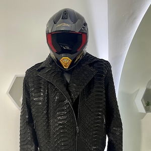 Peut inclure: Une veste en cuir noire avec un motif en peau de serpent. La veste a une fermeture éclair et un col montant.