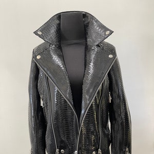 May include: A black leather jacket with a snakeskin pattern and silver hardware. The jacket has a zipper closure and a stand-up collar.