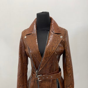 May include: A brown leather jacket with a snakeskin pattern, a zipper closure, and a belt at the waist.