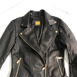 May include: Black leather jacket with a snakeskin pattern, gold zipper accents, and a black belt with a gold buckle.
