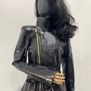 May include: Black leather jacket with a snakeskin pattern and gold zippers. The jacket has a high collar and a belted waist.