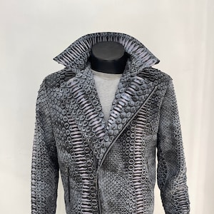 以下が含まれることがあります： ジッパー留めとスタンドカラーの黒とグレーのヘビ革ジャケット