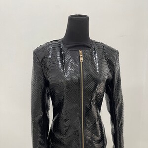 May include: A black leather jacket with a snakeskin pattern and a gold zip.