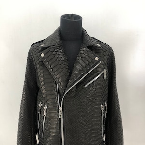 May include: A black leather jacket with a snakeskin pattern. The jacket has a zip closure, two zipped pockets on the chest, and two zipped pockets on the waist.