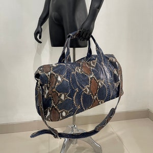 May include: A blue and brown snakeskin duffel bag with a long strap.