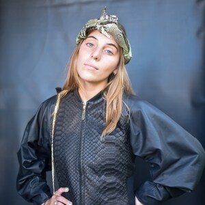 May include: A woman wearing a black leather jacket with a snakeskin pattern, a black skirt, and a headband with a snake design.