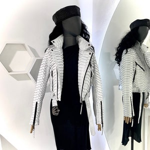 以下が含まれることがあります： 蛇柄の白い革のジャケット。ジッパーで閉めることができ、丈が短く、襟があります。