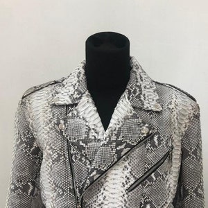 May include: A white and gray snakeskin leather motorcycle jacket with a zipper closure and a belt.