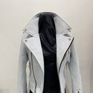 May include: White leather jacket with a snakeskin pattern and gold zippers.