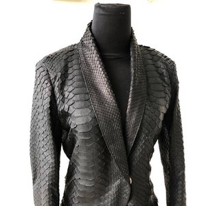 May include: A black snakeskin blazer with a shawl collar and a single button closure.