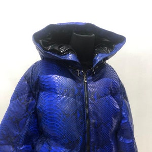 May include: A blue snakeskin puffer jacket with a black hood and zipper closure.