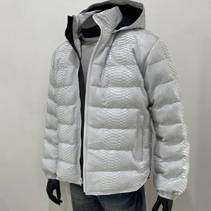 May include: A white puffer jacket with a snakeskin pattern. The jacket has a hood and a zip closure.