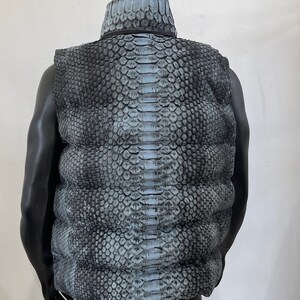 May include: A sleeveless puffer vest with a snakeskin pattern in shades of gray and blue.