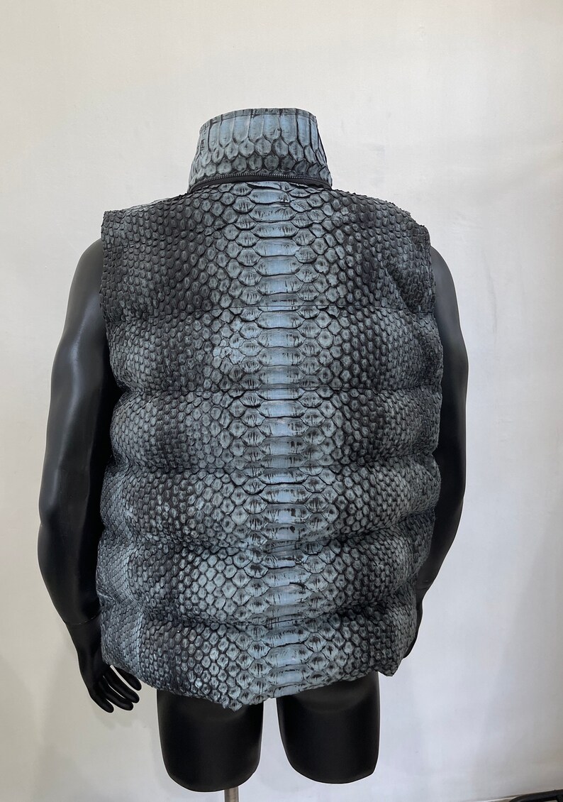 May include: A sleeveless puffer vest with a snakeskin pattern in shades of gray and blue.