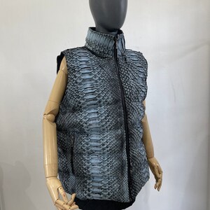 May include: A sleeveless puffer vest made of blue and black snakeskin with a zip closure.