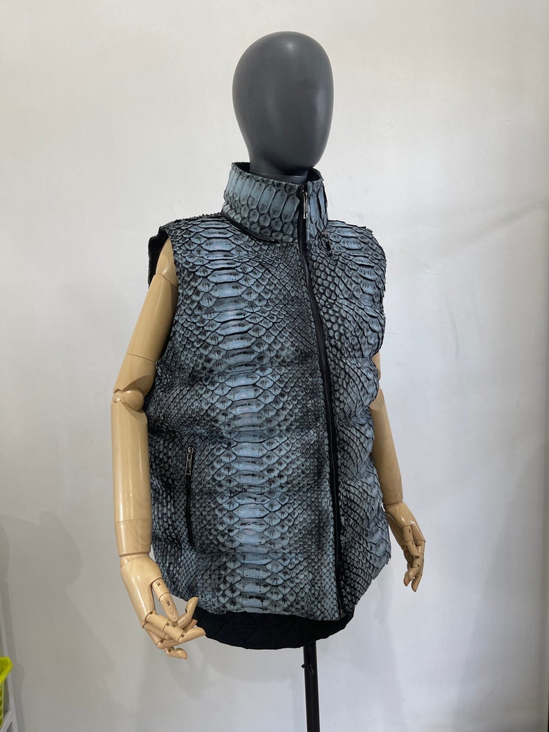 May include: A sleeveless puffer vest made of blue and black snakeskin with a zip closure.