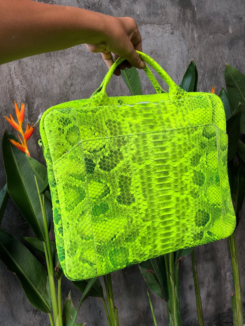 May include: A bright neon green snakeskin laptop bag with a zip closure and two handles.
