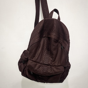 May include: A brown snakeskin backpack with adjustable straps and a zipped pocket on the front.