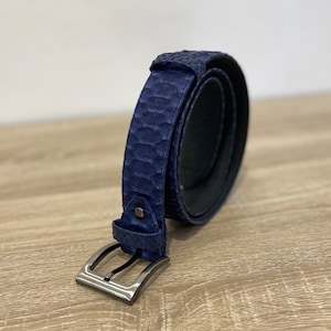 May include: A dark blue leather belt with a silver buckle. The belt is made of a textured material that resembles snakeskin.