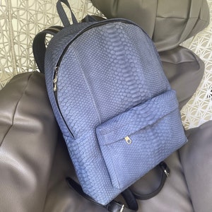 May include: A blue snakeskin backpack with a zipped front pocket and adjustable straps.