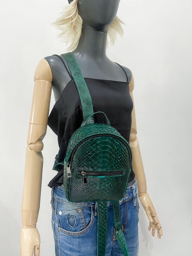Peut inclure: Un petit sac &agrave; dos en cuir de serpent vert avec une fermeture &eacute;clair et des bretelles r&eacute;glables.