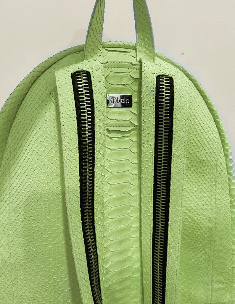 May include: A lime green snakeskin backpack with two zippered compartments and a silver metal tag that says "Obelp".