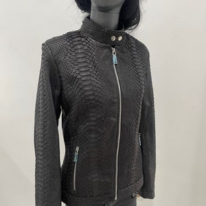 May include: Black leather jacket with a snakeskin pattern. The jacket has a zip closure and two zipped pockets.