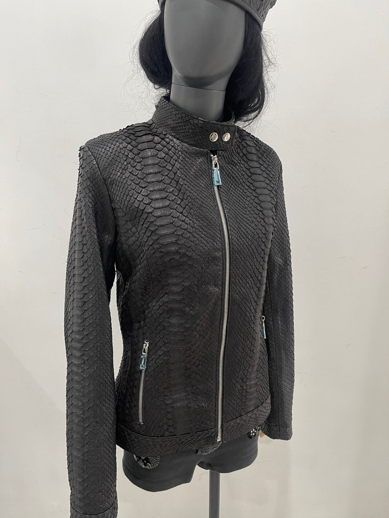 May include: Black leather jacket with a snakeskin pattern. The jacket has a zip closure and two zipped pockets.