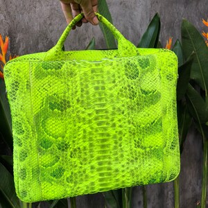 May include: A bright neon green snakeskin laptop bag with a top handle.