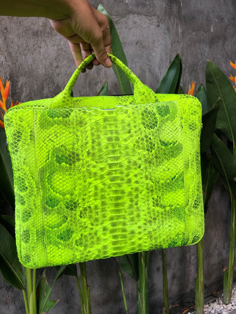 May include: A bright neon green snakeskin laptop bag with a top handle.